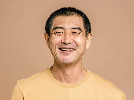 Middle aged man wearing a yellow shirt smiles at the camera