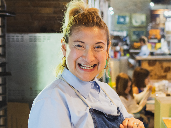 Woman wearing an apron and working in café with a big smile